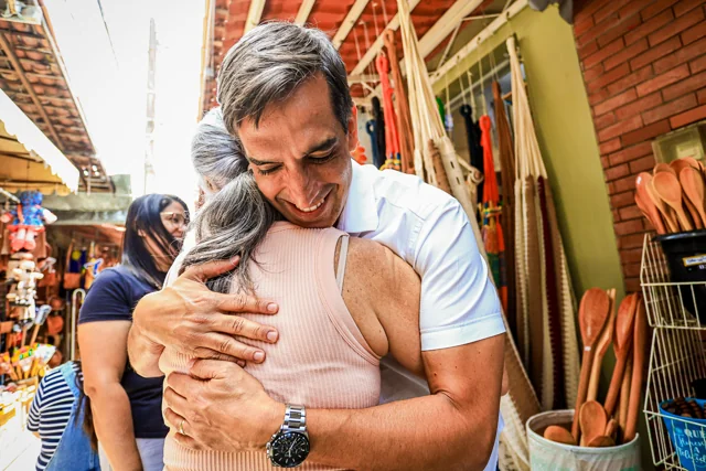 Fábio abraçando uma mulher em um espaço de comércio.