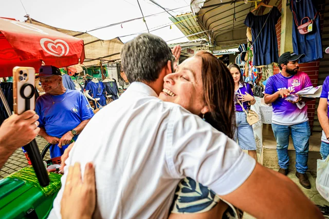 Fábio abraça uma mulher em uma feira.